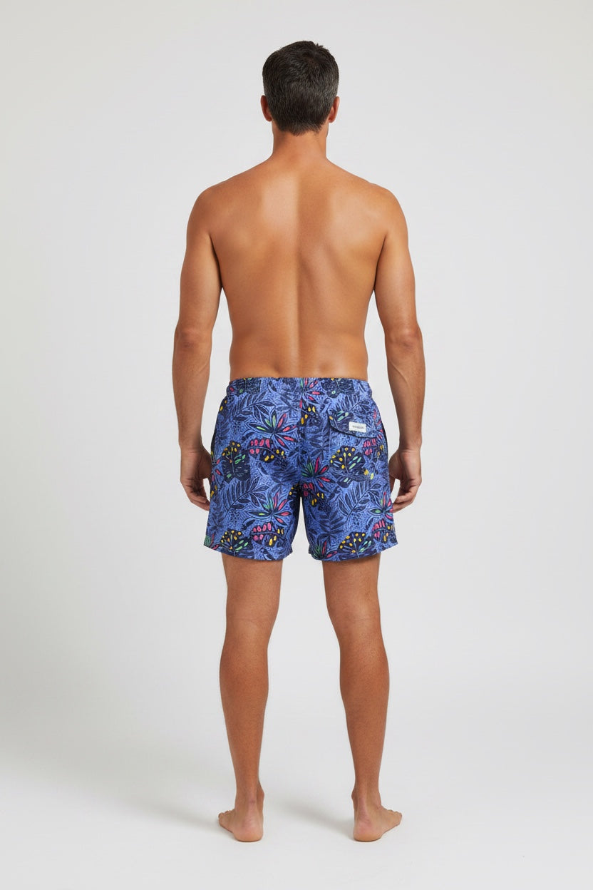98 Coast Ave men's swim shorts in deep blue with a multicolored tropical leaf print and white drawstring waist, model, back view