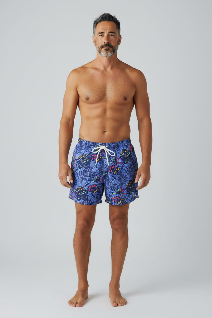98 Coast Ave men's swim shorts in deep blue with a multicolored tropical leaf print and white drawstring waist, model, front view