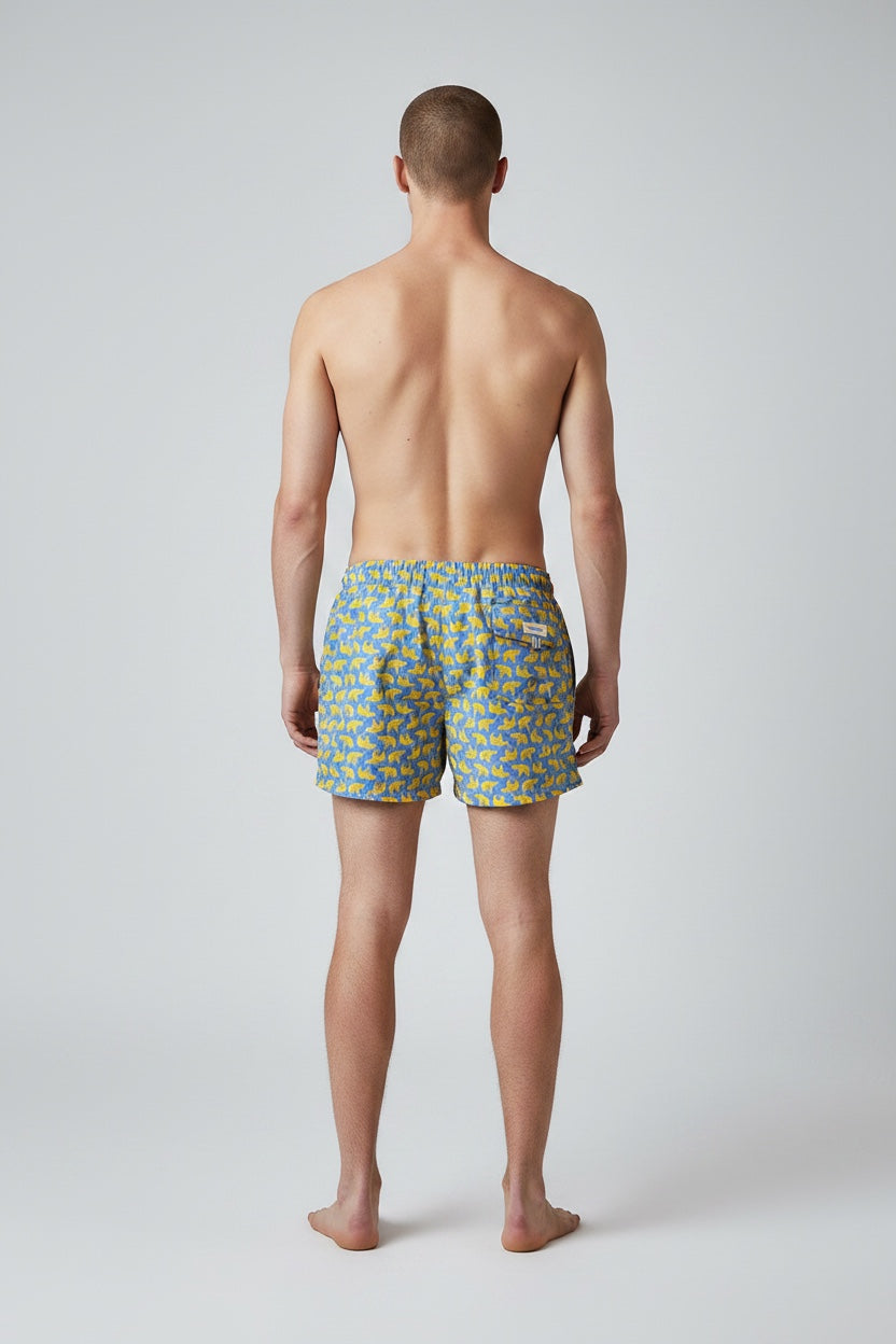 Model wearing 98 Coast men's blue and yellow elephant print swim short, back view showing fit and length.