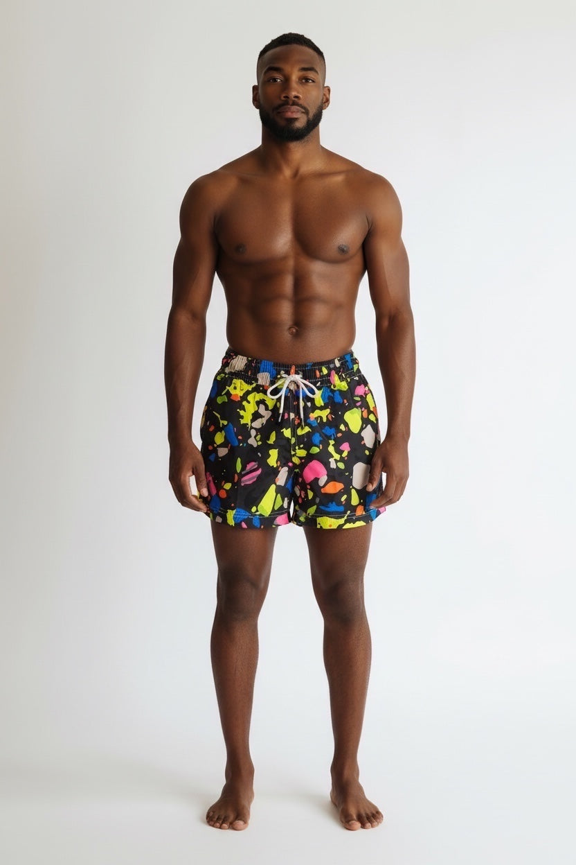 98 CoastAv. men's black swim shorts with vibrant multicolor paint splatter print, elastic waistband and drawstring, back pocket detail, model, front view