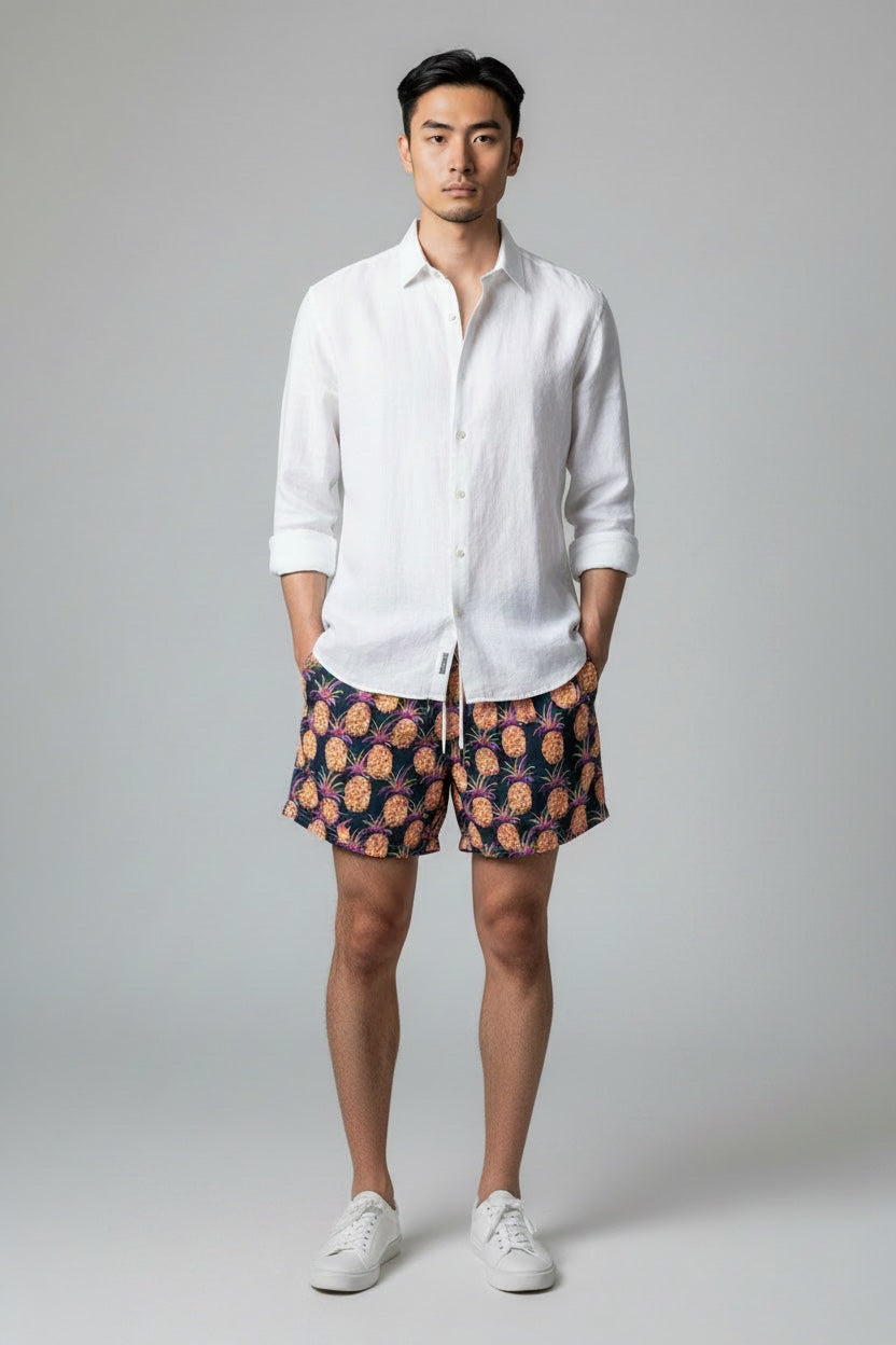 98 Coast Av. men's navy blue swim shorts with tropical pineapple print, elastic waistband and white drawstring, model wearing white shirt, front view