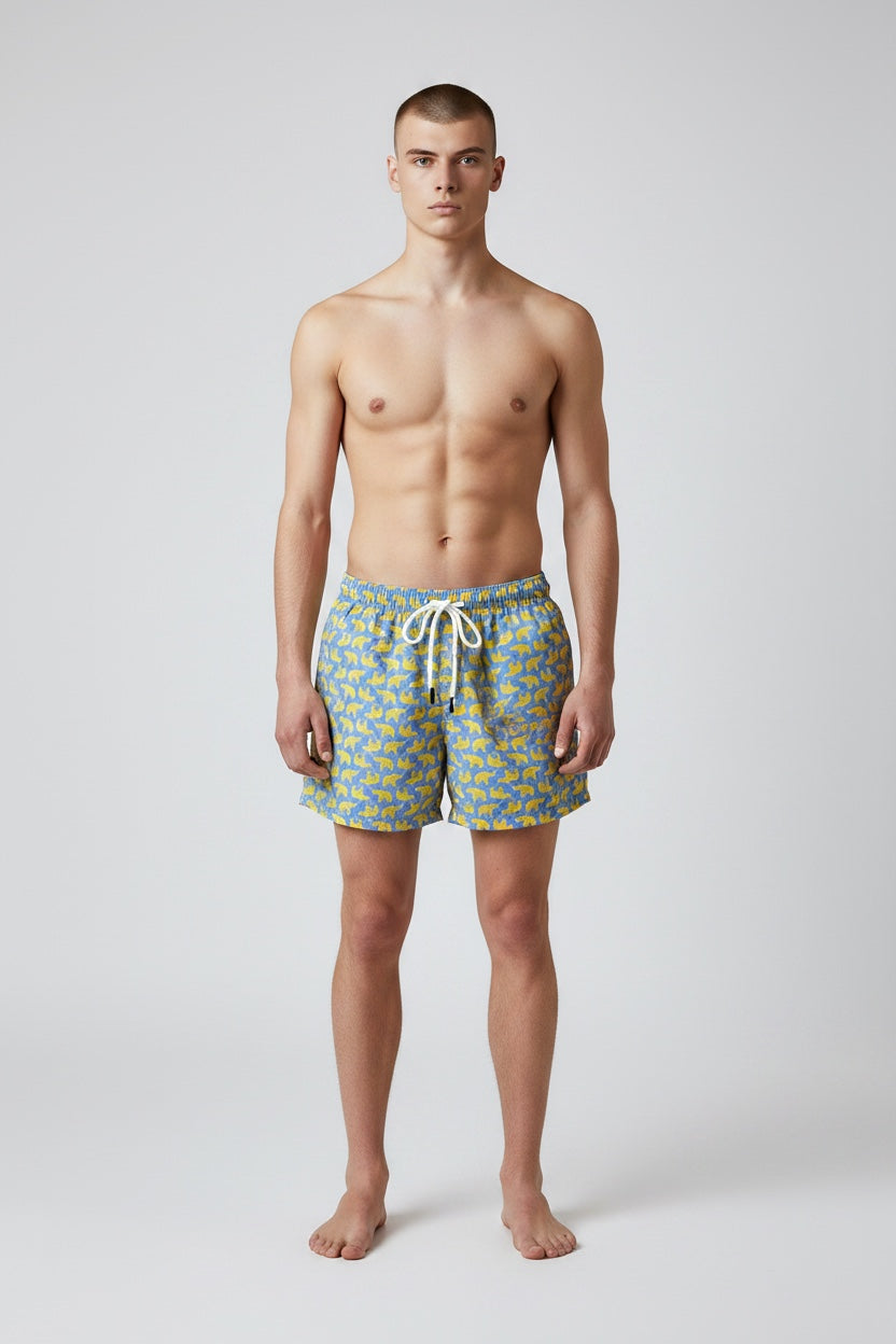 Model wearing 98 Coast men's blue and yellow elephant print swim short, front view showing fit and length.