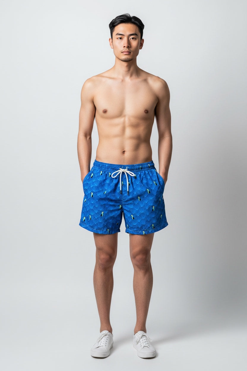 Model wearing 98 Coast men's blue toucan print swim shorts, elastic waist band and back pocket  detail. styled with a white shirt, model, front view