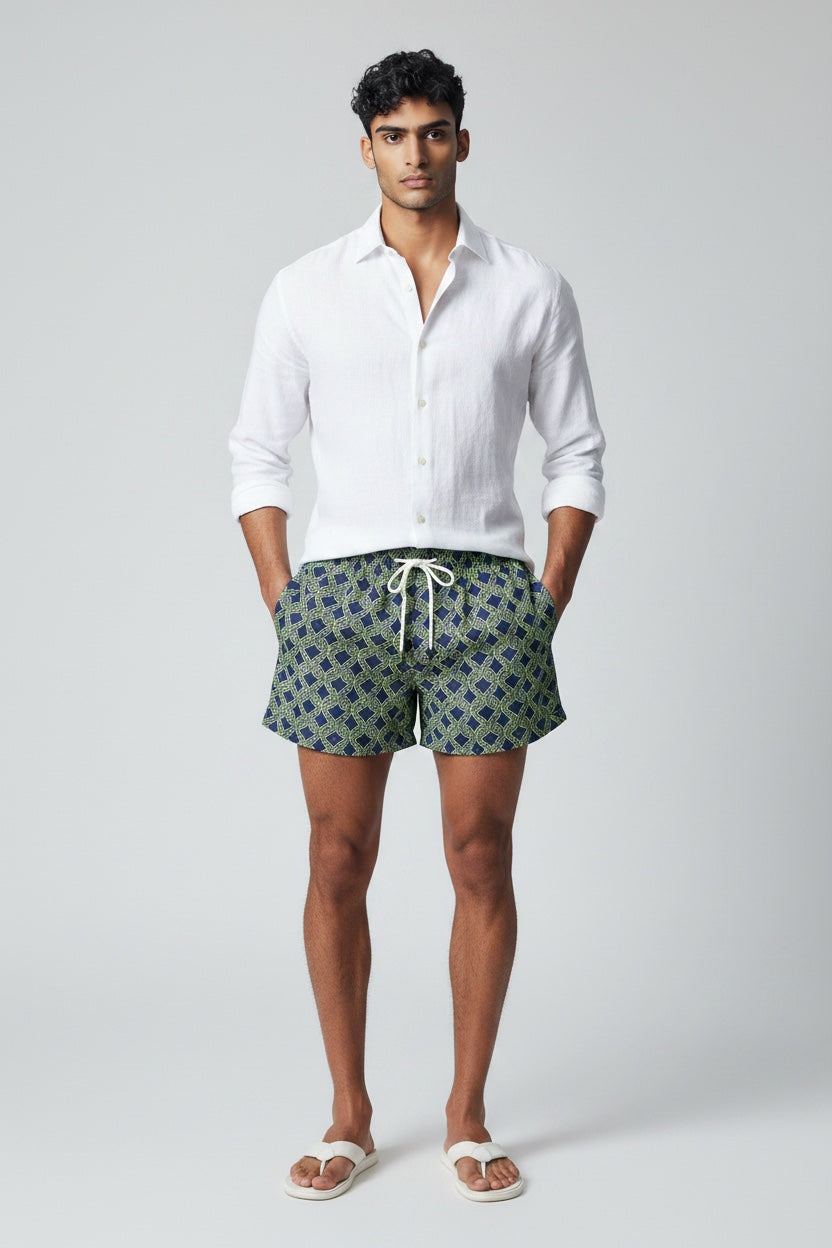 98 Coast men's navy blue swim shorts with a lime green nautical rope print, elastic waistband, drawstring, model with white shirt for a casual look, front view
